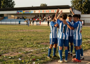 Futbolistas catalanes celebran victoria en amistoso de pretemporada en campo municipal bajo luz dorada de verano