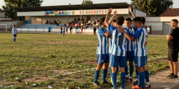 Futbolistas catalanes celebran victoria en amistoso de pretemporada en campo municipal bajo luz dorada de verano