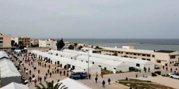Campamento humanitario en Ceuta con tiendas blancas y bandera española, reflejando la crisis del plan de 309 millones