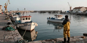 Pescador con flotas amarradas en puerto del norte de España al amanecer, símbolo de la crisis del sector pesquero español.