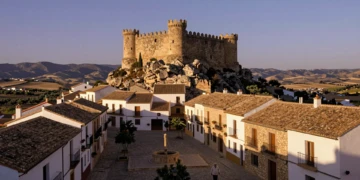 Castillo medieval en lo alto de un pueblo de Murcia con casas encaladas y calles empedradas al atardecer