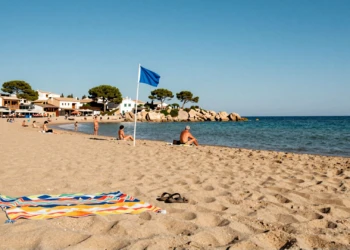 Playa tranquila con bandera azul en Dehesa de Campoamor, Alicante, con agua turquesa y arena dorada en agosto