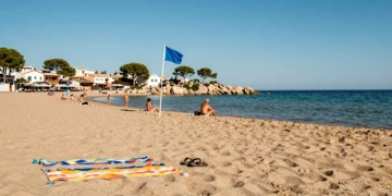 Playa tranquila con bandera azul en Dehesa de Campoamor, Alicante, con agua turquesa y arena dorada en agosto
