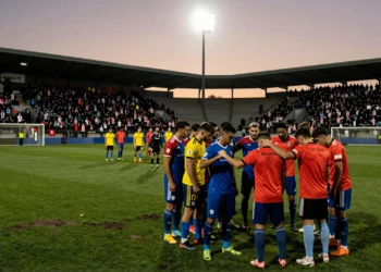 Jugadores con brazaletes de luto en estadio español al atardecer durante la primera ronda de la Copa del Rey