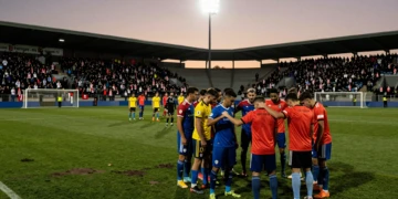 Jugadores con brazaletes de luto en estadio español al atardecer durante la primera ronda de la Copa del Rey